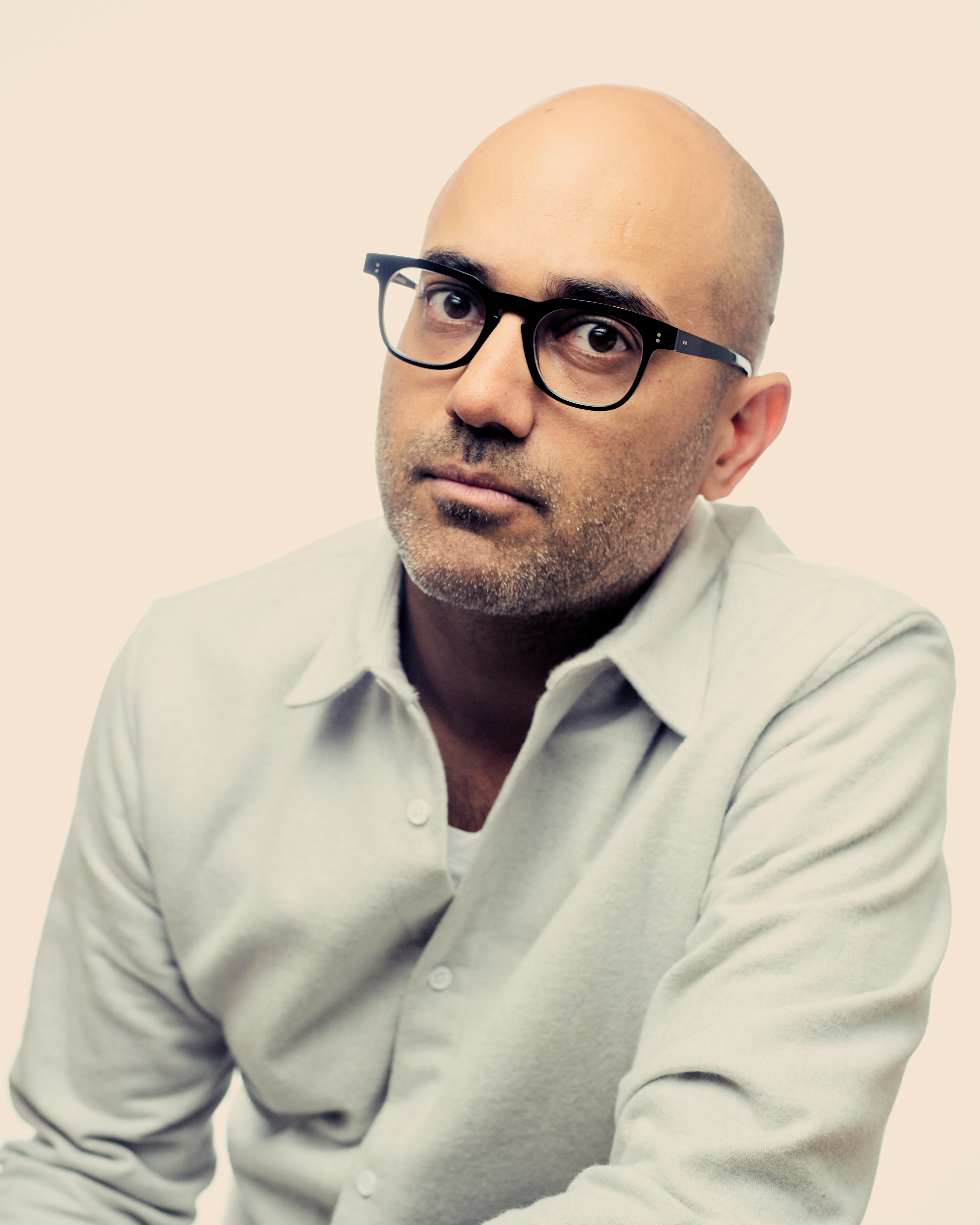 Head shot of Ayad Akhtar in a cream colored collared shirt,